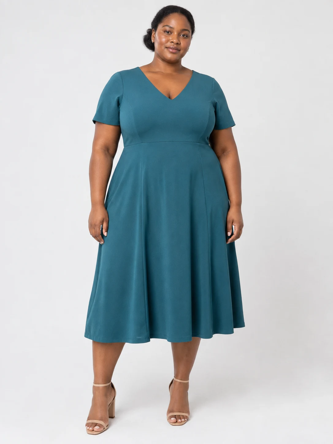 Plus-size fashion model wearing a teal midi dress in a clean PDP photograph